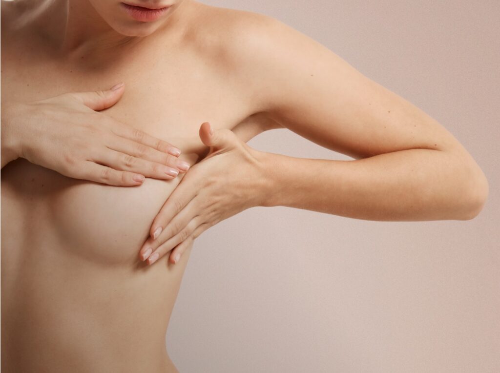 Side view of woman lifting breast to show breast droopiness