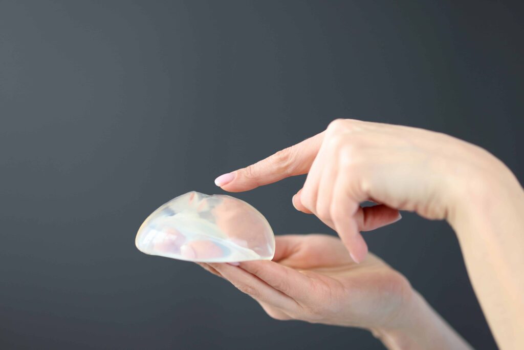 Surgeon holding a breast implant during breast implant removal consultation